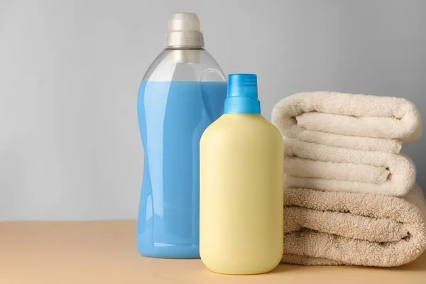 Flaschen Weichspüler Und Gestapelte Saubere Handtücher Auf Hellgelbem Tisch Vor — Stockfoto