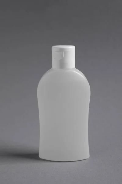 Bottle with cosmetic product on grey background