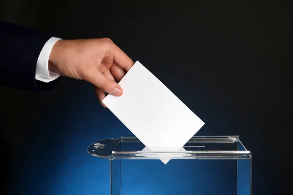 ダークブルーの背景に投票ボックスに投票する男 クローズアップ — ストック写真