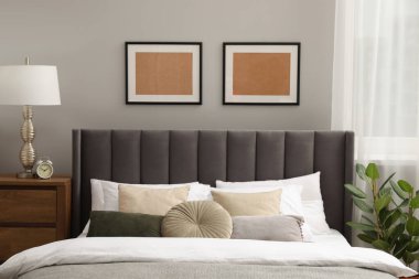 Yastıkları, lambası ve odasındaki ahşap çekmecelerde farklı dekorları olan rahat bir yatak. Şık iç mekan