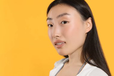 Turuncu arka planda makyajlı güzel bir genç kadın. Metin için boşluk