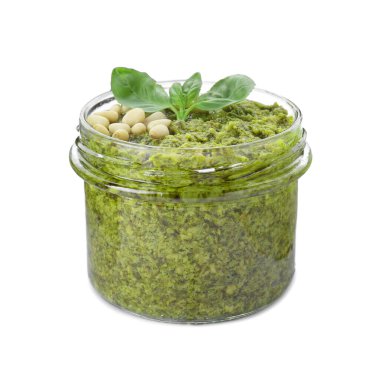 Lezzetli pesto soslu kavanoz, çam fıstığı ve fesleğen yaprakları beyaz üzerine izole edilmiş.