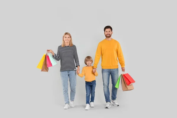家庭购物 快乐的父母和儿子 带着许多色彩艳丽的书包 背景浅灰色 — 图库照片