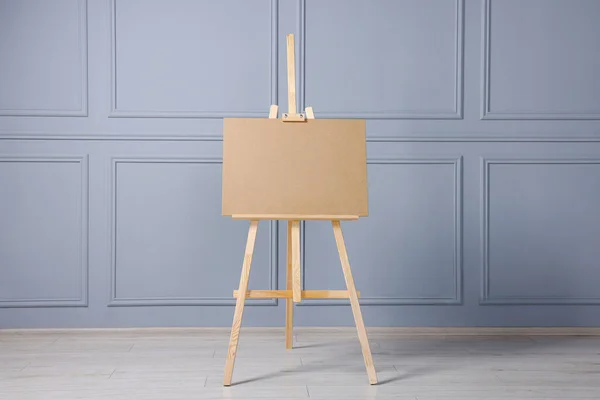 stock image Wooden easel with blank board near grey wall indoors