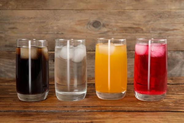 木製のテーブルの上に氷のキューブと異なるさわやかなソーダ水のメガネ — ストック写真