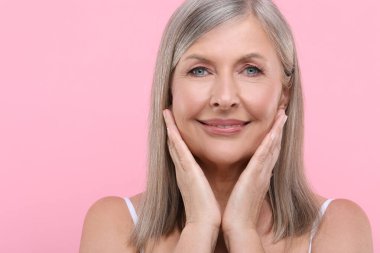 Portrait of beautiful senior woman on pink background