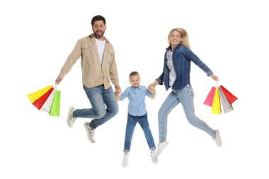 Aile alışverişi. Mutlu ebeveynler ve kızlar beyaz arka planda renkli çantalarla zıplıyorlar.