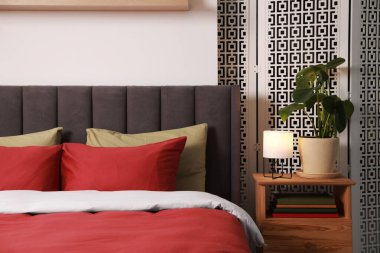 Şık bir yatak odası. Konforlu yatak odası, komodin ve yeşil çiçekli.