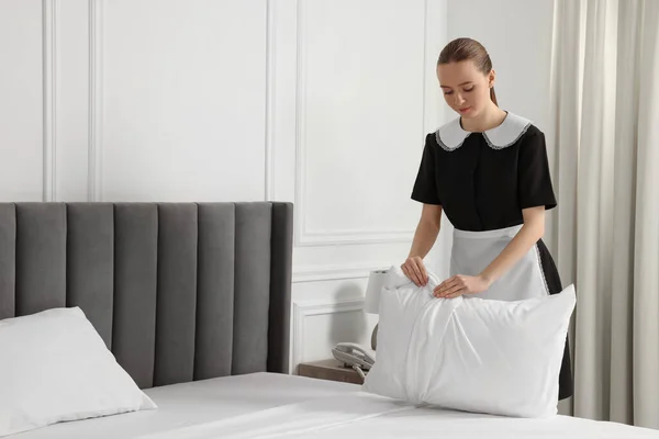 年轻的女仆在酒店房间铺床 文本的空间 — 图库照片
