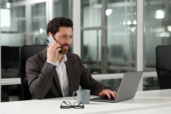 Чоловік Розмовляє Телефону Під Час Роботи Ноутбуком Білому Столі Офісі — стокове фото