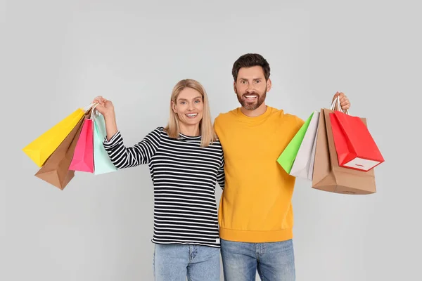 家庭购物 一对快乐的夫妇 背着许多色彩艳丽的包包 背景浅灰色 — 图库照片