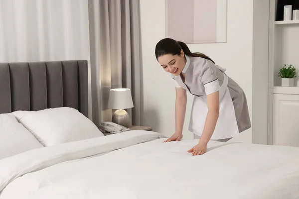 ホテルの部屋でベッドを作る若い女中 — ストック写真