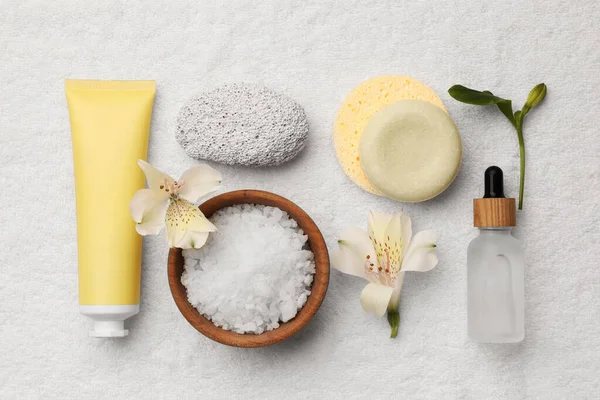 Flat lay composition with spa products and flowers on white towel