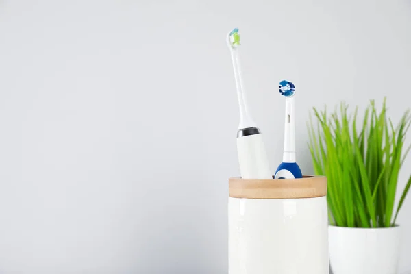 Escovas Dentes Elétricas Suporte Planta Sala Verde Fundo Claro Espaço — Fotografia de Stock