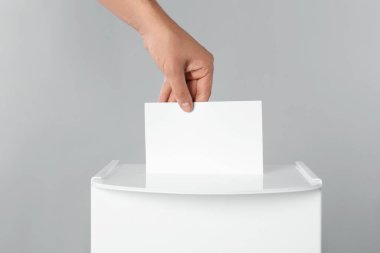 Adam oyunu açık gri arka planda sandığa koyuyor, yakın plan.