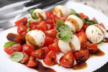 Domatesli Caprese salatası, mozzarella topları, fesleğen ve balzamik sirke tabakta, yakın plan.