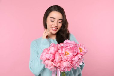 Pembe arka planda şakayık demeti olan güzel genç bir kadın.