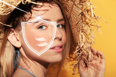 Sun protection care. Beautiful woman with sunscreen on face against golden background. Illustration of shield as SPF