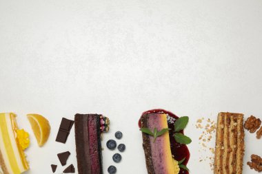 Aydınlık masa üzerinde farklı lezzetli pastalar içeren düz kompozisyon, metin için boşluk