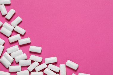 Pembe arka planda dişetleri çiğneyen lezzetli beyaz sakızlar.