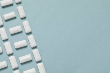 Açık mavi arka planda dişeti çiğneyen lezzetli, düz bir zemin. Metin için boşluk