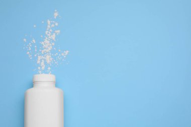 Açık mavi zemin üzerinde şişe ve dağınık toz tozu, üst görünümü metin için alan. Bebek kozmetik ürünü