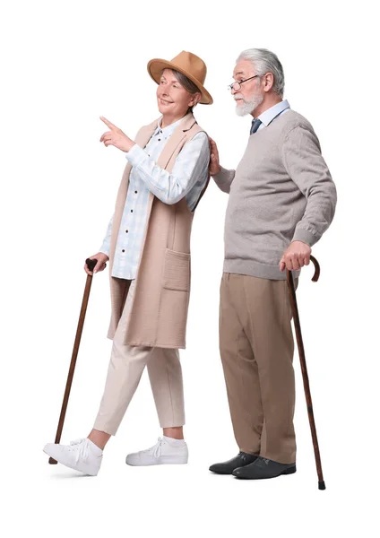 歩く杖を持つシニア男性と女性は白い背景に何かを見て — ストック写真