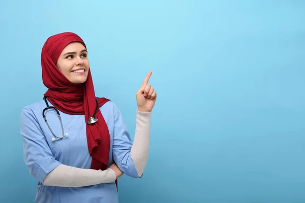 Mujer Musulmana Hiyab Uniforme Médico Señalando Algo Sobre Fondo Azul — Foto de Stock