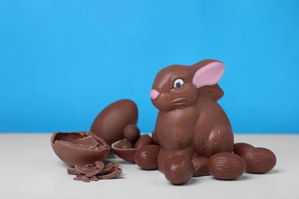 stock image Chocolate Easter bunny and eggs on white table against light blue background