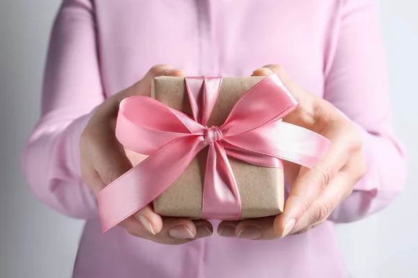 女人拿着粉红蝴蝶结礼盒 背景浅灰 — 图库照片