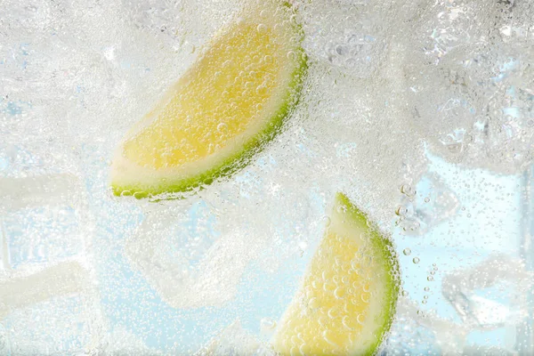 Sappige Limoenschijfjes Ijsblokjes Sodawater Tegen Lichtblauwe Achtergrond Close — Stockfoto