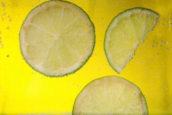 Succose Fette Lime Acqua Gassata Sfondo Giallo Primo Piano — Foto Stock