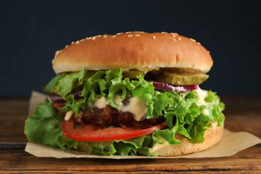 Köfteli leziz burger ve ahşap masada marul, yakın plan.