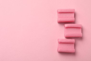 Tasty chewing gums on pink background, flat lay. Space for text