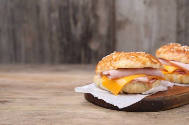 Ahşap masada jambon ve peynirli leziz simit, metin için yer.