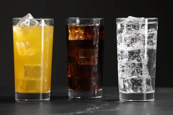 Gri Masanın Üzerinde Buz Küpleri Olan Farklı Tazeleyici Soda Bardakları — Stok fotoğraf