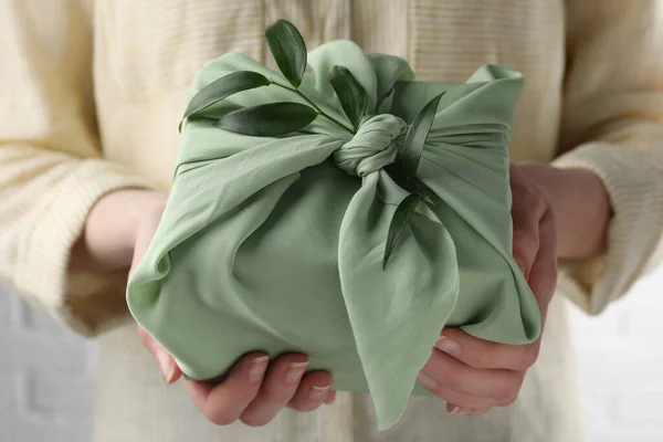 Furoshiki技巧女人拿着用绿色面料包装的礼物 用红花枝装饰 — 图库照片