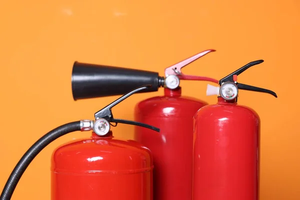 Tre Röda Brandsläckare Orange Bakgrund Närbild — Stockfoto