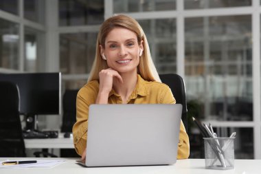 Ofisteki beyaz masada dizüstü bilgisayarda çalışan kadın.