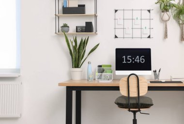 Bilgisayarlı, modern mobilyalı ve evdeki ev bitkileriyle rahat bir iş yeri.