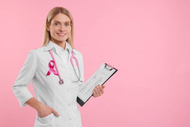 Pembe kurdeleli doktor, not panosu ve steteskop renkli arka plan, yazı için yer. Göğüs kanseri farkındalığı