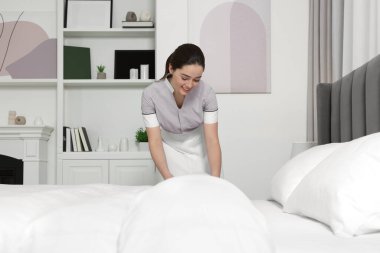 Otel odasında yatak yapma genç Oda hizmetçisi