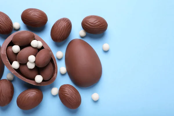 Deliciosos Huevos Chocolate Caramelos Sobre Fondo Azul Claro Puesta Plana —  Fotos de Stock