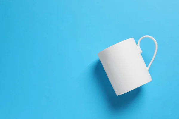 stock image One white ceramic mug on light blue background, top view. Space for text