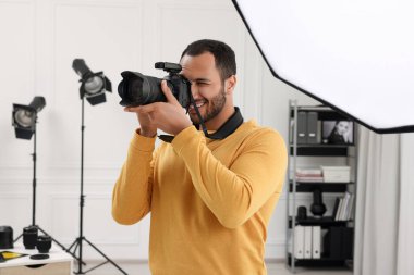 Modern fotoğraf stüdyosunda fotoğraf çeken genç profesyonel fotoğrafçı.