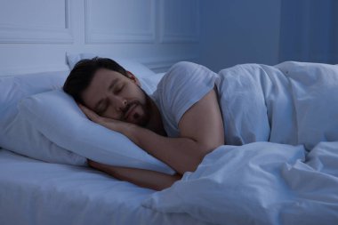 Geceleri yatakta uyuyan yakışıklı adam.