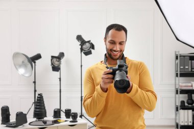 Modern fotoğraf stüdyosunda kamerası olan genç profesyonel fotoğrafçı.