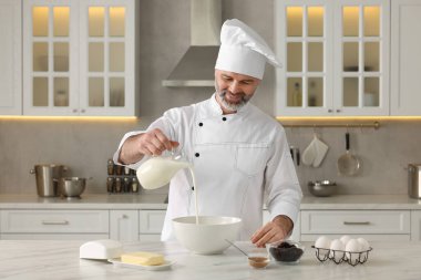 Profesyonel şef mutfaktaki beyaz mermer masada hamur yapıyor.