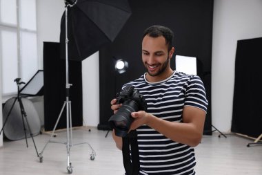 Modern fotoğraf stüdyosunda kamerası olan genç profesyonel fotoğrafçı.