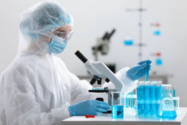 Laboratuvarda mikroskopla çalışırken bilim adamı test tüpü alıyor.